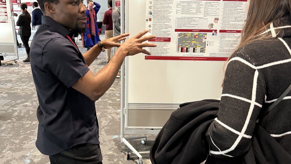 A student presents their poster at a poster session